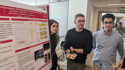 Two male students and one female student standing next to their research poster. 