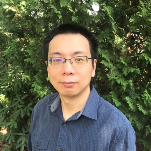 Head shot of Asian male with short black hair and eyeglasses wearing a blue button down shirt.