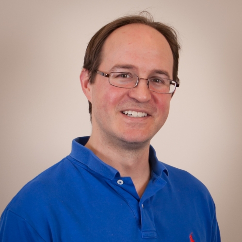 Head shot of balding male with eyeglasses and wearing a blue polo shirt.