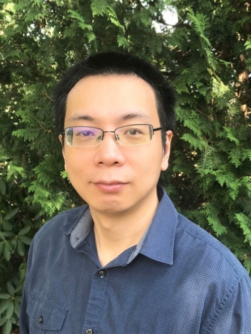 Head shot of Asian male with short black hair and eyeglasses wearing a blue button down shirt.