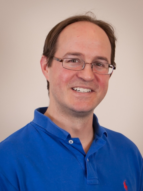 Head shot of balding male with eyeglasses and wearing a blue polo shirt.