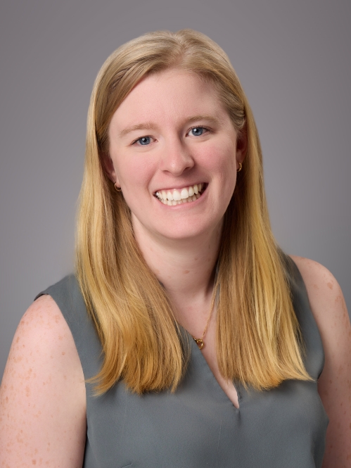 Headshot of female with long blonde hair wearing a sleeveless grey blouse.
