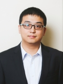 Head shot of Asian male with short black hair, eyeglasses wearing a black suit jacket with a white button down shirt.