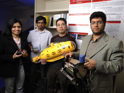 A female student with two male students and a male professor holding yellow submersible