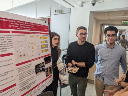 Two male students and one female student standing next to their research poster. 