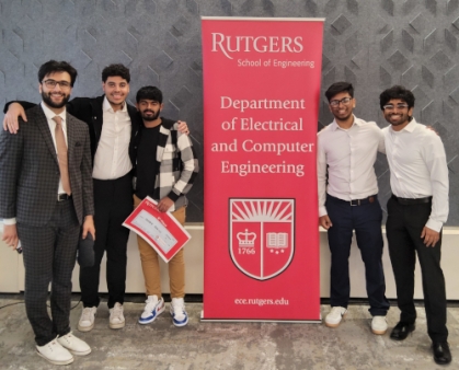 Group of students standing next to a red banner.