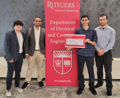 Four male students flank a red Rutgers Department of Electrical and Computer Engineering banner.