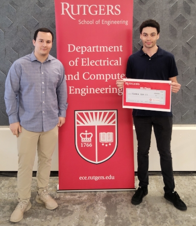 Two male students flank a red Rutgers Department of Electrical and Computer Engineering banner.