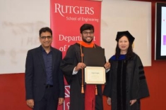 Arpan Gupta holds his diploma while standing between two professors