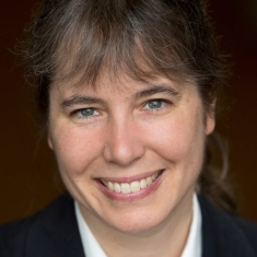 Head shot of smiling woman with brown hair and bangs.