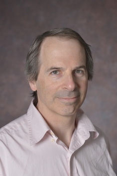 Headshot of male with short dark grey hair wearing a button down shirt.
